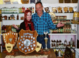 Boet en sy vrou Martie wys na die verskeidenheid bottels mampoer en likeurs en van die toekennings wat hulle al gewen het. Foto: Dustin Wetdewich