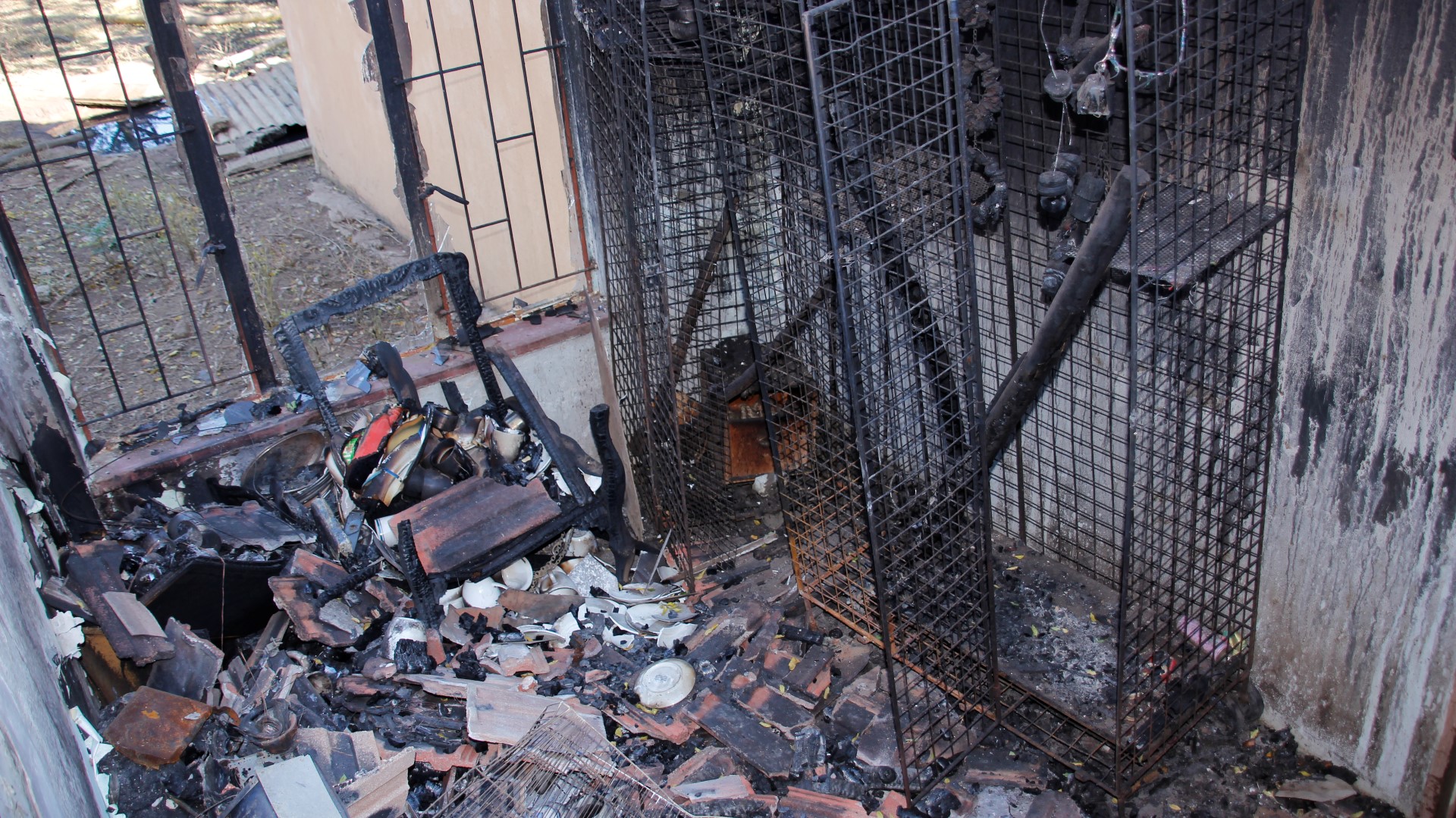 Susan de Wet by die verbrande inhoud van hul huis nadat hulle alles verloor het behalwe die slaapklere wat sy die aand van die brand aangehad het. Die egpaar het selfs hul geliefde diere-kinders in die brand verloor. Foto: Teresa Holloway