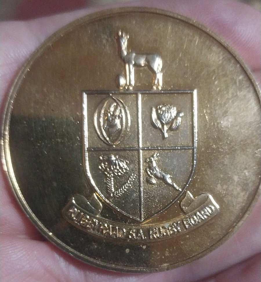 A gold coin featuring an intricate coat of arms design on its surface.